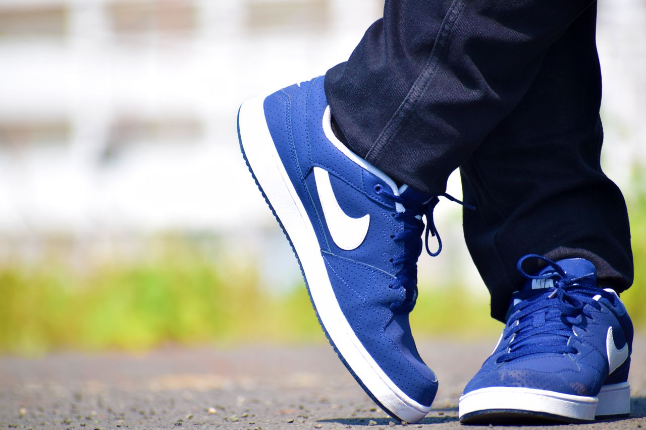 Home Blue Nike sneakers worn by adult on outdoor pavement, showcasing urban street fashion.