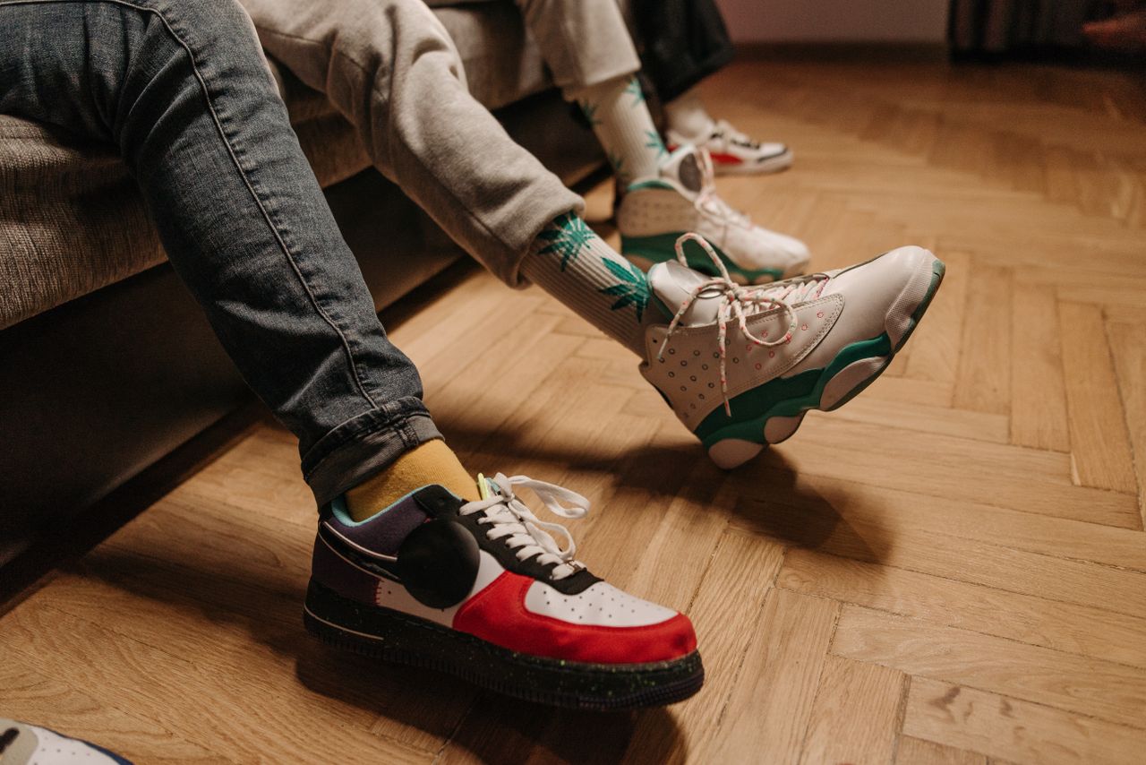Home Close-up of legs in colorful sneakers relaxing indoors on wooden floor.