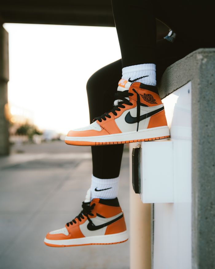 Home Close-up of orange sneakers and socks against an urban backdrop, highlighting street fashion.